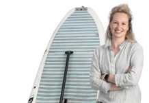 the prop Carrie Gill poses with a paddleboard, symbolizing her love for being on the water.