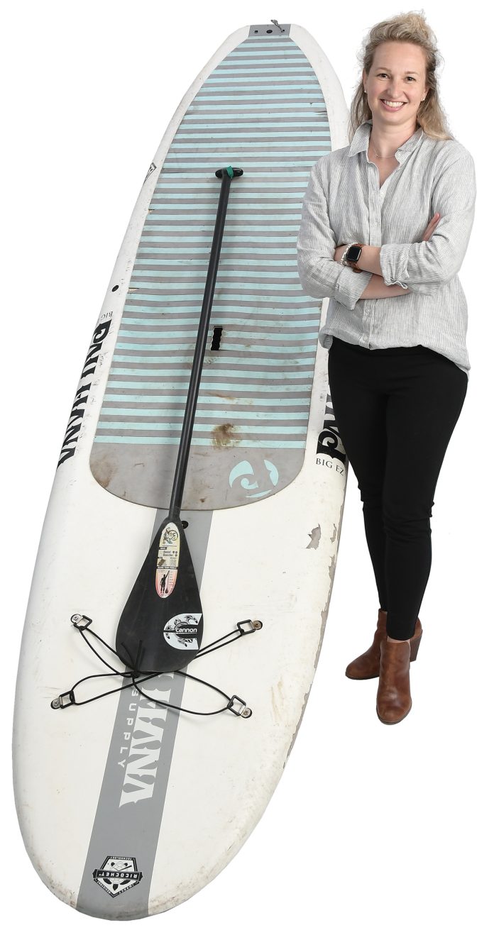 the prop Carrie Gill poses with a paddleboard, symbolizing her love for being on the water. the prop Carrie Gill poses with a paddleboard, symbolizing her love for being on the water.