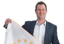 the prop Eric Lichatin holds the Rhode Island state flag, defining where he’s from and who he is.