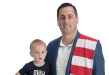 the prop Michael J. Medeiros poses with his son, Joseph, along with a couple soccer balls and a U.S. Soccer scarf.