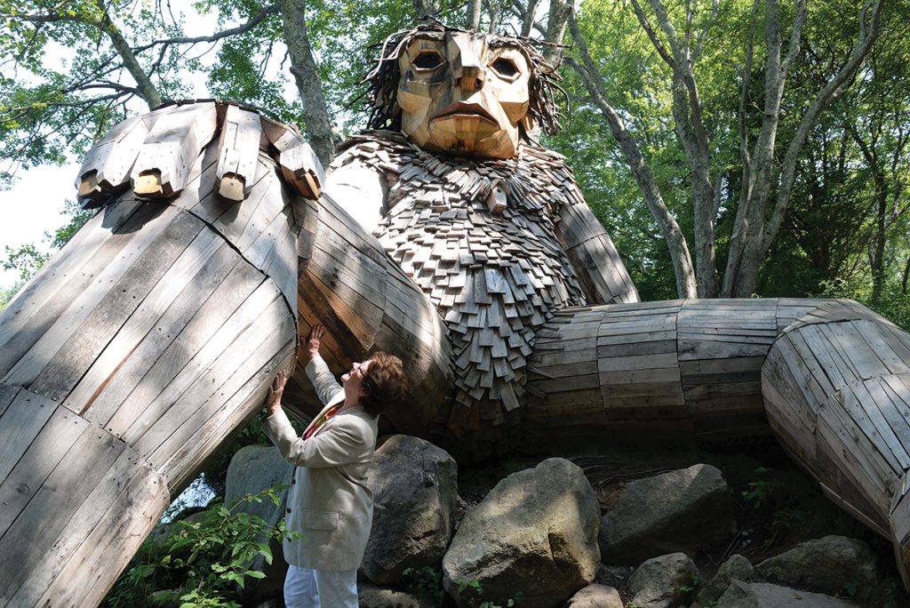 TROLL SIGHTING: Louise Bishop, South County Tourism Council CEO and president, visits one of the two trolls living in the woods of Ninigret Park in Charlestown. Bishop says the trolls, made of recycled materials, have drawn 100,000 visitors this year alone. Three more trolls have been installed recently in Rhode Island.  PBN PHOTO/ ELIZABETH GRAHAM