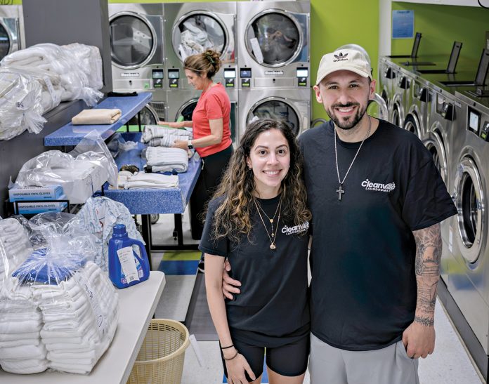 ALL IN THE FAMILY: James Manzo and fiancée Vanessa Fonseca, co-owners of Cleanville Laundromat in Smithfield, with laundry attendant Maggi Fonseca folding clothes in the background.  PBN PHOTO/MICHAEL SALERNO