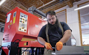 STEELY GAZE: Noel Laflamme, a technician at metal fabricator Ward’s Manufacturing LLC in Warren, measures the thickness of a steel plate as he prepares for a job in the workshop.  PBN PHOTO/MICHAEL SALERNO