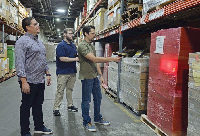 STORAGE SPACE: From left, Dean Warehouse Services Inc. Information Technology Director Cesar Ramirez, IT support technician Aiden Runk and System Administrator Jeremy Venditto work with the system they’ve developed to organize and locate stored items at the company’s Cumberland facility. PBN PHOTO/ELIZABETH GRAHAM