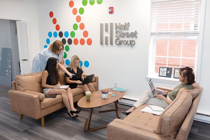 STRATEGIC PLANNING: From left, Half Street Group team members Nadia Engenheiro, digital and social media strategist; Account Director Hillary Lima; senior account executive Chelsea DeCesare; and account executive Kerri Tallman discuss a marketing plan at the public relations firm’s Providence office. PBN PHOTO/TRACY JENKINS