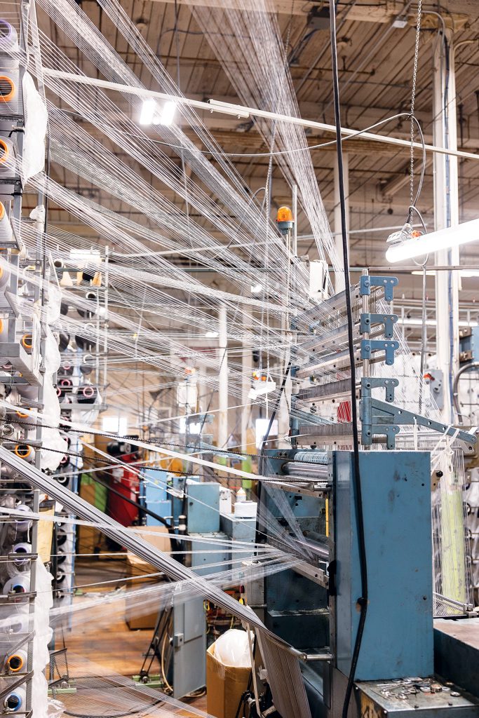 SPINNING: Machines spin fabric into yarn and other materials at North East Knitting Inc.’s manufacturing facility in Pawtucket. PBN PHOTO/TRACY JENKINS