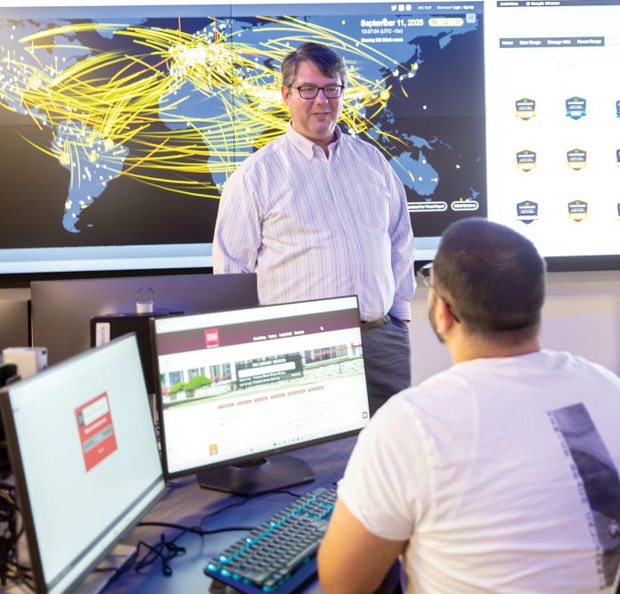 TRAINING GROUND: Douglas S. Alexander, director of the Institute for Cybersecurity & Emerging Technologies at Rhode Island College, speaks with RIC senior Miled Kalbourji in the institute’s new cyber range classroom. COURTESY RHODE ISLAND COLLEGE