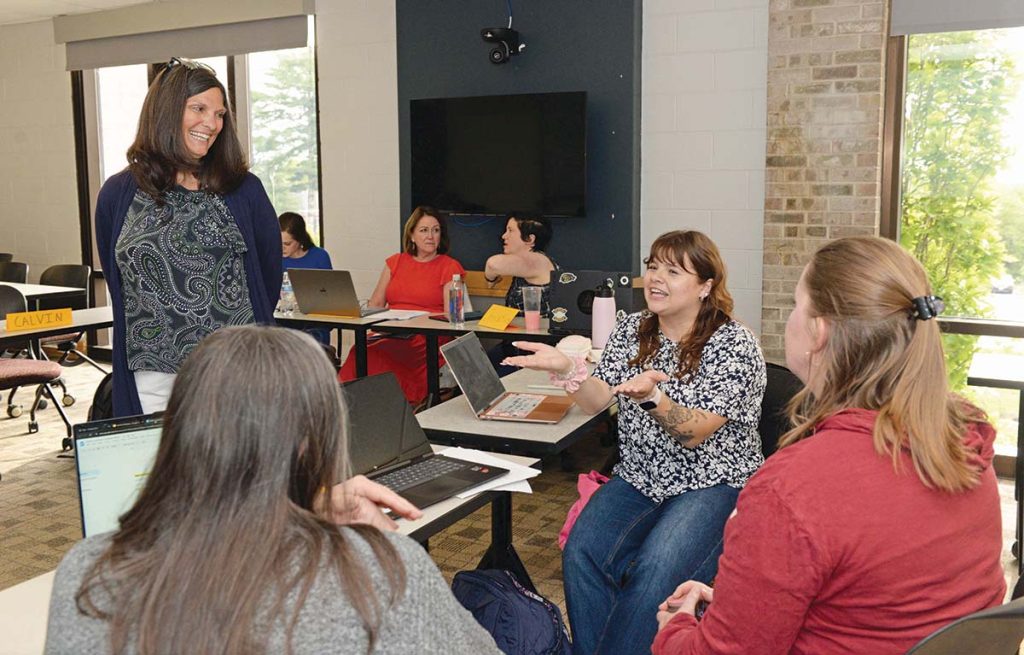 CLASS DISCUSSION: Annemarie Vaccaro, standing, dean and professor at the Feinstein College of Education, teaches a class on ­higher education at the University of Rhode Island. She is speaking with students, from left, Kelly Richmond, Kaitlin Bevins and Cassie Santiago. PBN PHOTO/ELIZABETH GRAHAM 