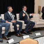 DOUGLAS ALEXANDER, seated at right, director of the Institute for Cybersecurity & Emerging Technologies at Rhode Island College, speaks during a panel discussion at Providence Business News' Cybersecurity, AI & Tech Summit at Crowne Plaza Providence-Warwick. Alexander was joined on the panel by, from left, David Phillips, chief information security officer at OSHEAN Inc., and Rick Norberg, CEO at Vertikal6 Inc. Guest moderator is Norman Duquette, standing, senior vice president at Starkweather & Shepley Insurance Brokerage Inc. / PBN PHOTO/MIKE SKORSKI