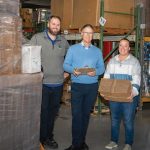 Inside the box: Atlantic Paper’s human touch fuels manufacturing success TAKING STOCK:
David Spencer, center, owner and CEO of Atlantic Paper & Supply, works
with JC Lebarron, left, part of the operations team, and Ashley Femino, sales coordinator, at the company’s Pawtucket facility.
PBN PHOTO/JOSH EDENBAUM