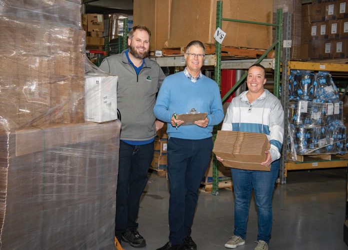 TAKING STOCK:  David Spencer, center, owner and CEO of Atlantic Paper & Supply, works  with JC Lebarron, left, part of the operations team, and Ashley Femino, sales coordinator, at the company’s Pawtucket facility. PBN PHOTO/JOSH EDENBAUM