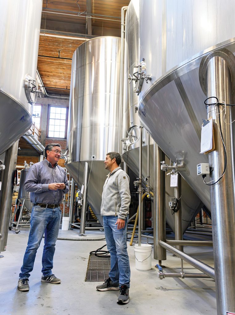 EVOLVING INDUSTRY: Jeremy Duffy, left, and Devin Collins, co-founders and managing partners at The Guild Brewery in Pawtucket, discuss the shifts in the craft beer brewing industry. PBN PHOTO/MICHAEL SALERNO  