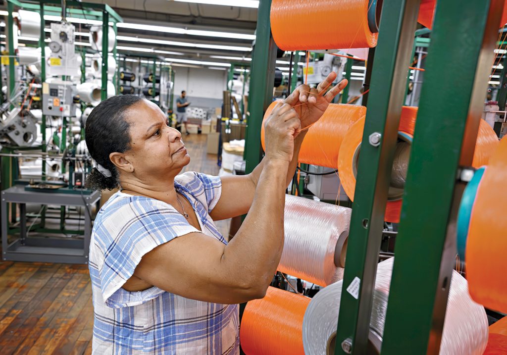 STRING SKILLS: Machine operator Maria Dacruz works on the production floor of Neocorp Inc., a standard and technical rope and bungee cord maker in Pawtucket. Neocorp is among the local manufacturers that have dealt with inflated tariffs in 2025.  PBN PHOTO/ MICHAEL SALERNO