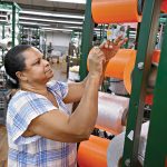 STRING SKILLS: Machine operator Maria Dacruz works on the production floor of Neocorp Inc., a standard and technical rope and bungee cord maker in Pawtucket. Neocorp is among the local manufacturers that have dealt with inflated tariffs in 2025.  PBN PHOTO/ MICHAEL SALERNO