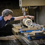 CAREFUL CRAFTING: Machinist Troy Hawkins takes a measurement while setting up the equipment at Hawkins Machine Co. in Coventry. Hawkins is the fourth generation of the family to work at the company, which is feeling the squeeze of rising costs.  PBN PHOTO/MICHAEL SALERNO