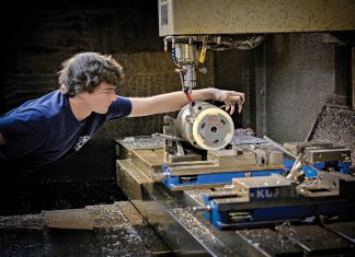 CAREFUL CRAFTING: Machinist Troy Hawkins takes a measurement while setting up the equipment at Hawkins Machine Co. in Coventry. Hawkins is the fourth generation of the family to work at the company, which is feeling the squeeze of rising costs.  PBN PHOTO/MICHAEL SALERNO
