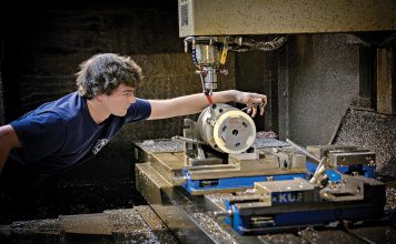 CAREFUL CRAFTING: Machinist Troy Hawkins takes a measurement while setting up the equipment at Hawkins Machine Co. in Coventry. Hawkins is the fourth generation of the family to work at the company, which is feeling the squeeze of rising costs.  PBN PHOTO/MICHAEL SALERNO