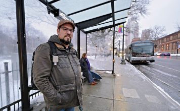 TIME CONSCIOUS: Barry Dejasu of East Providence waits at Kennedy Plaza to make his R.I. Public Transit Authority bus home after arriving on a bus from Warwick, where he works. RIPTA service changes have made his commute longer and more complex. PBN PHOTO/MICHAEL SALERNO