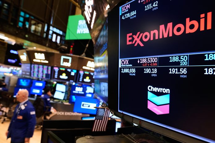 OIL COMPANY logos are displayed on the floor of the New York Stock Exchange on March 3. Gas prices in the Ocean State have increased 27 cents from a week ago to $3.15 per gallon, according to AAA Northeast. / AP PHOTO/SETH WENIG