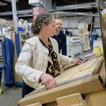 SHIPPING AND HANDLING: Hideaway Solutions LLC CEO Dana Pinnock boxes up one of the Bristol company’s fold-out step stools as owner-operator Lancelot Pinnock looks on. PBN PHOTO/MICHAEL SALERNO