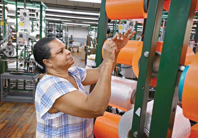 STRING SKILLS: Machine operator Maria Dacruz works on the production floor of Neocorp Inc., a standard and technical rope and bungee cord maker in Pawtucket. Neocorp was among the local manufacturers that dealt with inflated tariffs in 2025.
PBN FILE PHOTO/MICHAEL SALERNO STRING SKILLS: Machine operator Maria Dacruz works on the production floor of Neocorp Inc., a standard and technical rope and bungee cord maker in Pawtucket. Neocorp was among the local manufacturers that dealt with inflated tariffs in 2025.
PBN FILE PHOTO/MICHAEL SALERNO