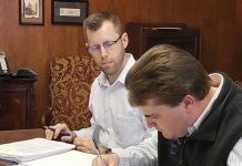 NEXT GEN: Chaffee Industrial Roofing President Peter Chaffee, foreground, officially marks the fourth generation of family ownership in 2019, signing paperwork transferring ownership in the presence of an unidentified lawyer.  COURTESY CHAFFEE INDUSTRIAL ROOFING
