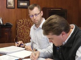 NEXT GEN: Chaffee Industrial Roofing President Peter Chaffee, foreground, officially marks the fourth generation of family ownership in 2019, signing paperwork transferring ownership in the presence of an unidentified lawyer.  COURTESY CHAFFEE INDUSTRIAL ROOFING