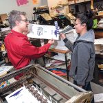 HELPING HAND: Dan Wood, owner and founder of DWRI Letterpress LLC print shop, works in 2008 with Lois Harada, shop manager, on the Polyman 50 automatic-fed cylinder letterpress at the shop’s headquarters in Providence.  PBN FILE PHOTO/MICHAEL SALERNO