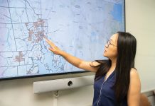 SPREADING OUT: University of Rhode Island public health professor Wenhui Feng examines a map of dollar stores in Rhode Island, most of them concentrated in urban areas. Feng is leading a new study on dollar stores and the food that is purchased there.  PBN PHOTO/STEPHANIE BERNABA