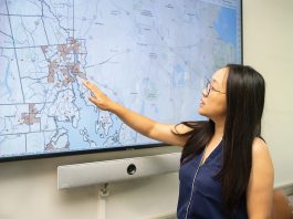 SPREADING OUT: University of Rhode Island public health professor Wenhui Feng examines a map of dollar stores in Rhode Island, most of them concentrated in urban areas. Feng is leading a new study on dollar stores and the food that is purchased there.  PBN PHOTO/STEPHANIE BERNABA