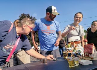 PRICE IS RIGHT: Jay Almeida, second from left, owner of Curio Estate Sales & Cleanouts LLC, haggles prices with the crowd at one of the estate sales his business organized in Cranston. PBN PHOTO/MICHAEL SALERNO