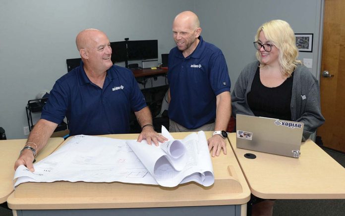FAR REACH: Avidex Industries LLC serves clients worldwide. From left, Bob Mathews, senior account executive; Thomas Ward, senior project manager; and Dominique Perrin, project coordinator, work on blueprints in Warwick.
PBN PHOTO /ELIZABETH GRAHAM FAR REACH: Avidex Industries LLC serves clients worldwide. From left, Bob Mathews, senior account executive; Thomas Ward, senior project manager; and Dominique Perrin, project coordinator, work on blueprints in Warwick.
PBN PHOTO /ELIZABETH GRAHAM