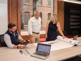 CONSTRUCTION CONVERSATION: Chris Maury, left, head of Rhode Island operations and head of preconstruction for the New England region; Gordon Zaniol, center, project executive; and Kristine Kennedy, senior project manager, discuss a project at Shawmut Design and Construction. PBN PHOTO/TRACY JENKINS