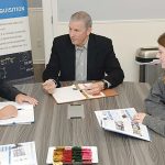 Pentagon rule drives Axiotrop growth COLLABORATIVE CONFERENCE: Joseph Devine, center, president of Axiotrop LLC, meets with Dewetron Inc. Head of Operations Albon Redzepi, left, and marketing specialist Gabriella Scott at Axiotrop’s Narragansett office.
PBN PHOTO/ELIZABETH GRAHAM