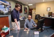 Starting Over: Christopher P. Devine, left, assistant vice president and branch manager at The Washington Trust Co., meets with bank teller Ashutosh Talukder, who took Community College of Rhode Island’s banking course after coming to the United States in 2025. PBN PHOTO/TRACY JENKINS