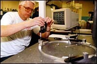 William Young checks the precisionof a machine part at TMC shop.(Photo, Brian McDonald) William Young checks the precision<br>of a machine part at TMC shop.<br>(Photo, Brian McDonald)