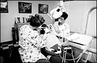 Dentists team up to work on a patient at the Joseph Samuels DentalCenter in Providence. Dentists team up to work on a patient<br> at the Joseph Samuels Dental<br>Center in Providence.