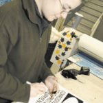 Michelle Collicci works on a sign remindingworkers to take caution around hazardousmaterials
