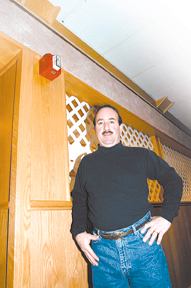 Dave Lombardi, of The 1025 inJohnston, stands below his recentlyinstalled fire alarm. Dave Lombardi, of The 1025 in<br>Johnston, stands below his recently<br>installed fire alarm.