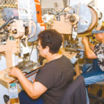 After mergers, company meetings integrate workers Elcinda DeAndrade adn Manuel DaRosa work on machines that tradmark jewelry at Curtis Manufacturing in Johnston. Curtis was acquired by The Colibri Group of Providence in June.