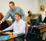Gtech learning services trainers John Metz, standing foreground, and Melissa Gould, standing background, work with colleagues to help them build new skills.