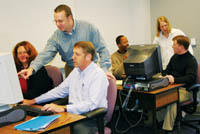 <b>Gtech</b> learning services trainers John Metz, standing foreground, and Melissa Gould, standing background, work with colleagues to help them build new skills. <b>Gtech</b> learning services trainers John Metz, standing foreground, and Melissa Gould, standing background, work with colleagues to help them build new skills.