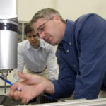 HEXAGON METROLOGY employees Frank Krazer, left, and Scott Everling test a coordinate measuring machine at the company's headquarters in North Kingstown. / 