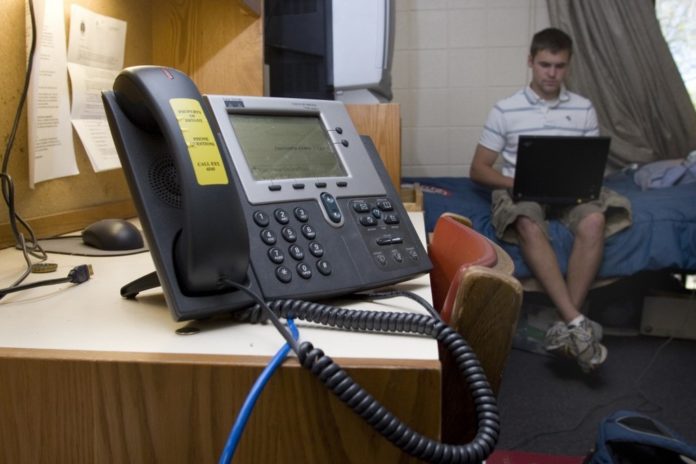 AT BRYANT UNIVERSITY, a voice over Internet protocol system is installed in each dorm. Screens on the phones can receive emergency messages. Here, Tom Madden, a junior, studies for his finals. / 