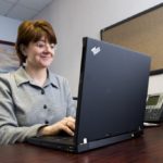 DENISE GUBATA, marketing coordinator at Lighthouse Computer Services, works on a laptop computer that has a wireless connection to the Internet. / 