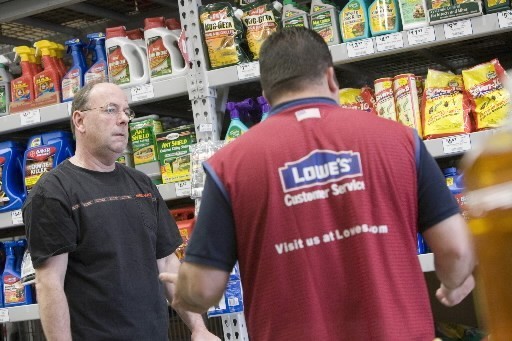AT LOWE'S in Natick, Mass., store manager Brian Rebello, right, yesterday explains termite products to customer Joe O'Brien. The chain has lowered its annual earnings forecast, citing the real estate slump that continues to pare home-improvement sales. / AT LOWE'S in Natick, Mass., store manager Brian Rebello, right, yesterday explains termite products to customer Joe O'Brien. The chain has lowered its annual earnings forecast, citing the real estate slump that continues to pare home-improvement sales. /