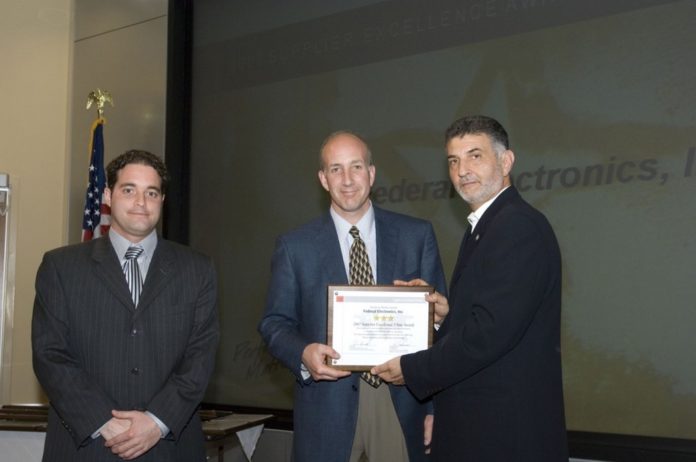 FEDERAL ELECTRONICS Inc. Account Manager Chris Heywood and VP Ed Evangelista accept the Supplier Excellence Award from Zack Noshirwani, integrated supply chain VP for Raytheon IDS. / 
