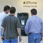 IN SALT LAKE CITY, three shoppers an iPhone demo on a giant model in the window of the Apple Store at Gateway Mall. / 