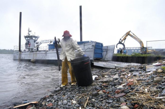 CLEAN THE BAY staffer Dave Tobler removes debris during the cleanup last Monday. / 