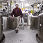 JIM RICH of Alexion Pharmaceuticals walks through an alley of buffer holding tanks at the Smithfield plant, which has been entirely renovated. / 